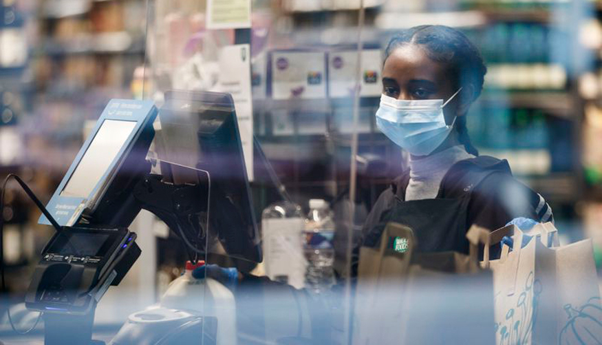 A cashier wears a mask while working at a Whole Foods Market in Washington, April 14, 2020.