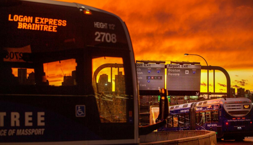 A Logan Express bus taking the airport exit at sunset