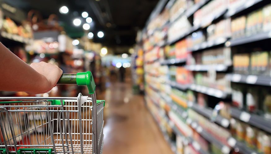 Shopping cart being pushed through grocery store.